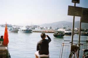 Man watches boats in a harbor with chinese flag